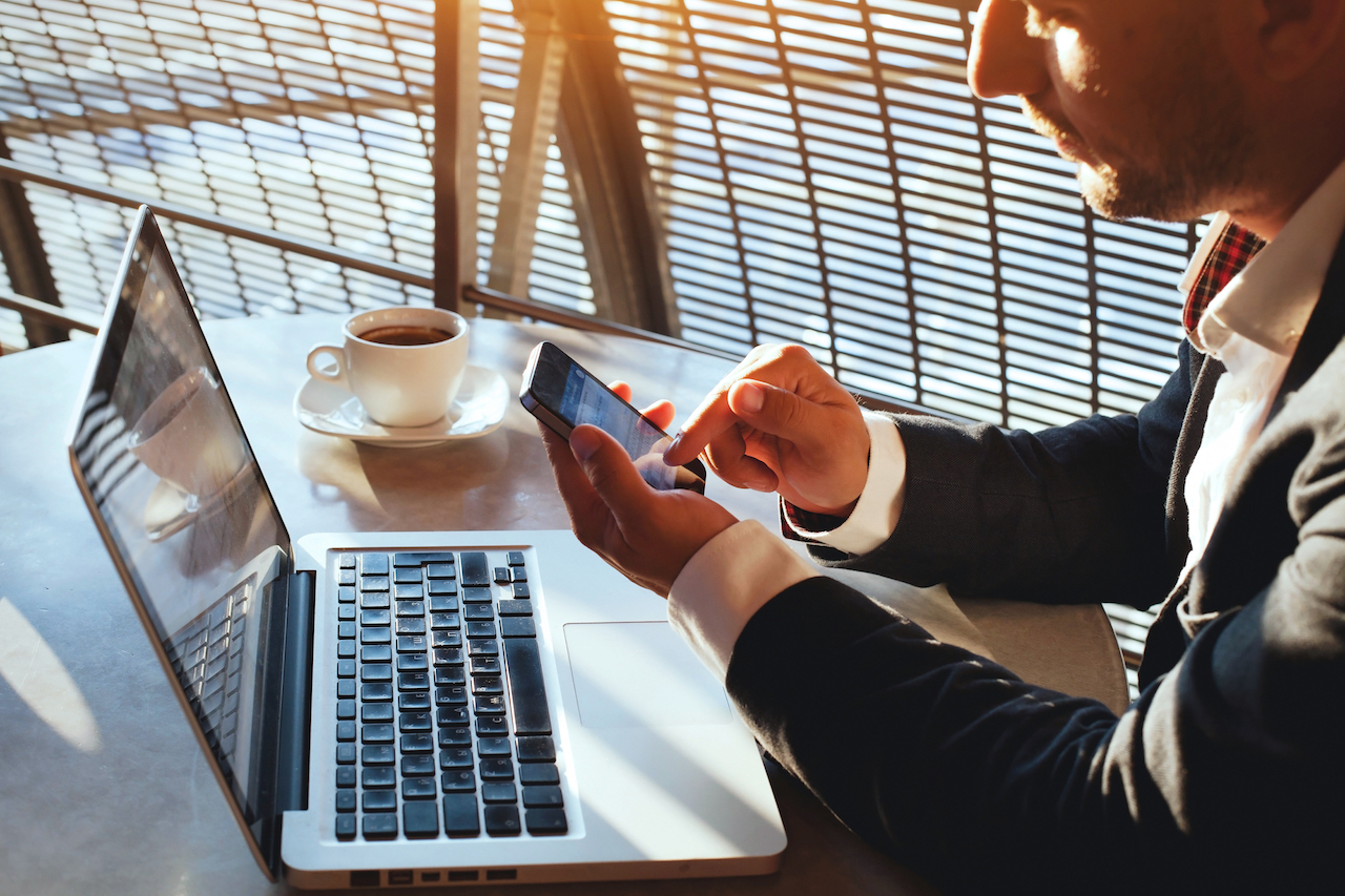 User interacting with a phone in front of a laptop