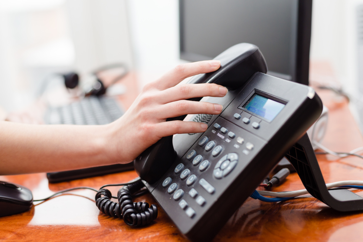 A hand just about to take the receiver off of the base of the phone.