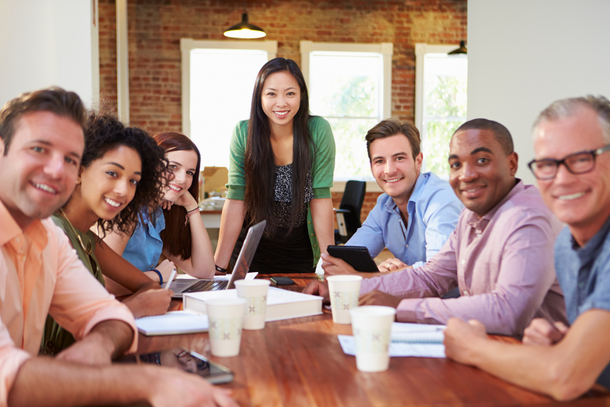 Woman standing over conference table with employees on either side