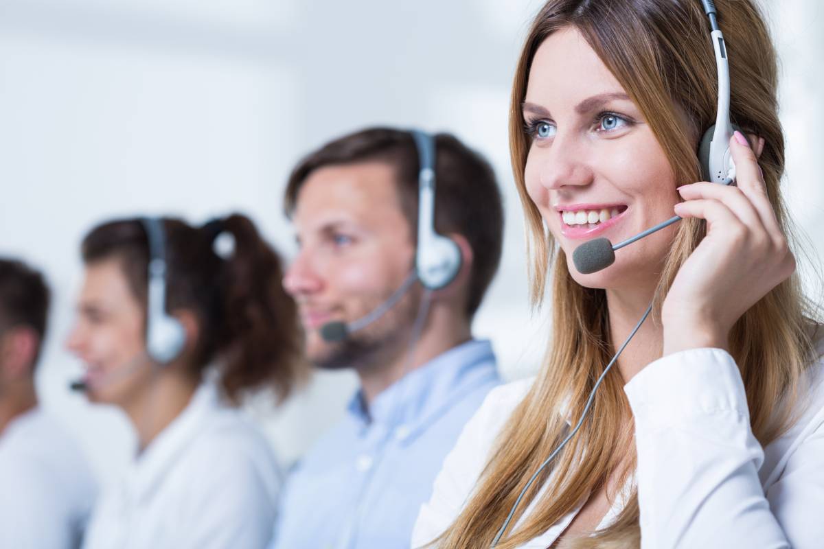 Woman who works at a call center smiling with three more employees blurred in the background.