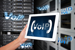 Hand in front of servers, holding a tablet that says 'VoIP'