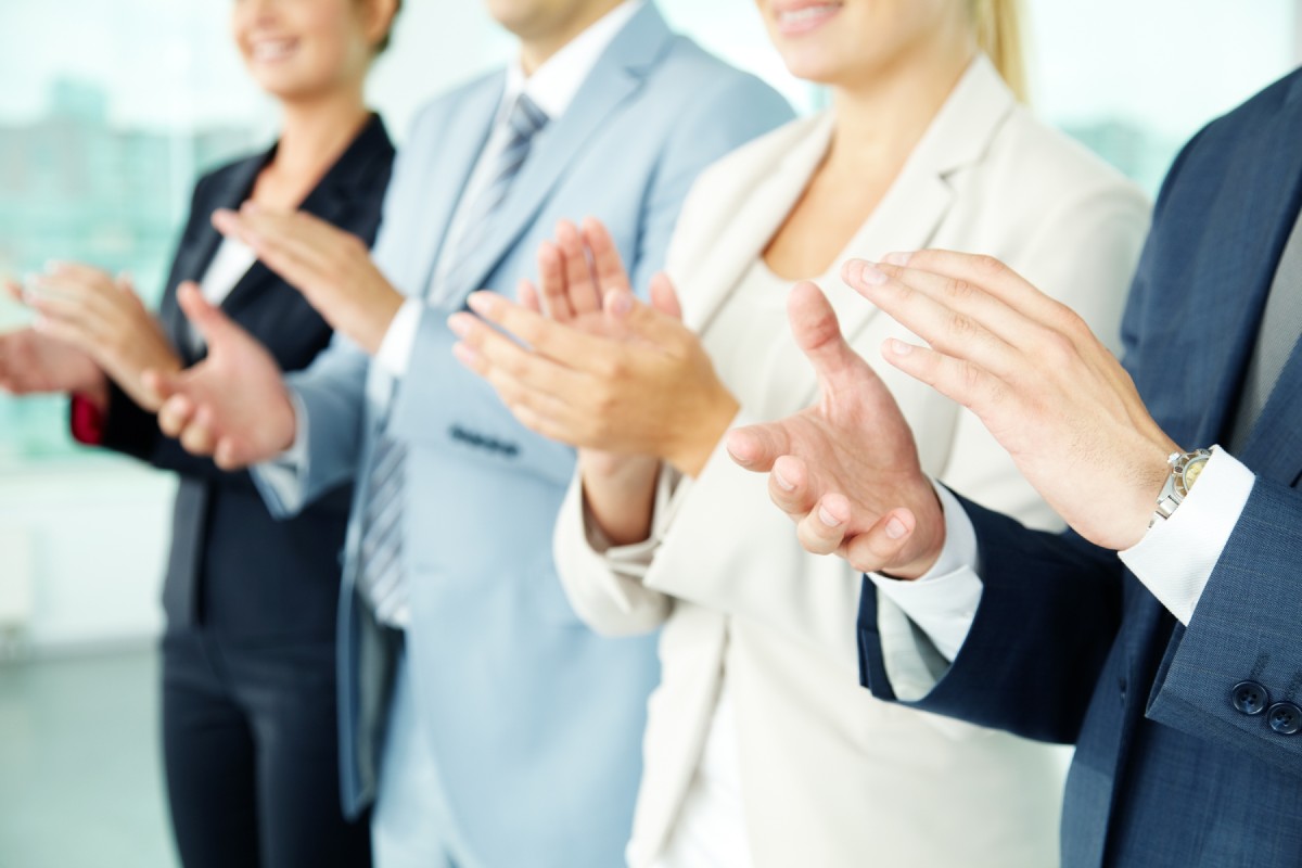 Two businessmen and two businewomen clapping in celebration