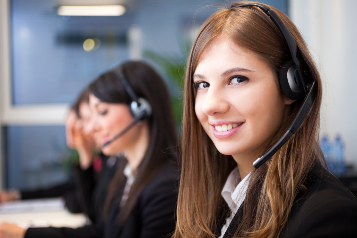 Woman in call center looking at the camera, 3 blurred co-workers behind her