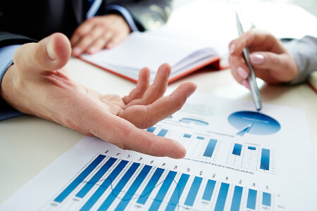 A close up of the hands of two people going over graphs and charts