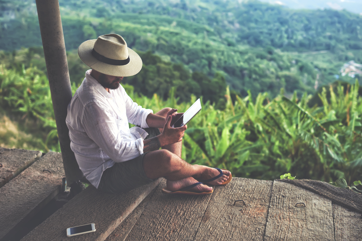 Man on Deck in Secluded Green Hillside Using Tablet